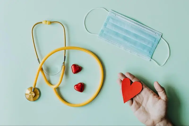 A face mask and paper hearts next to a stethoscope 