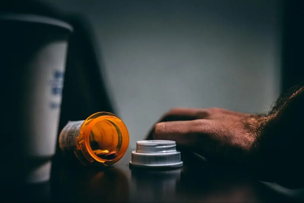 man with an open bottle of pills