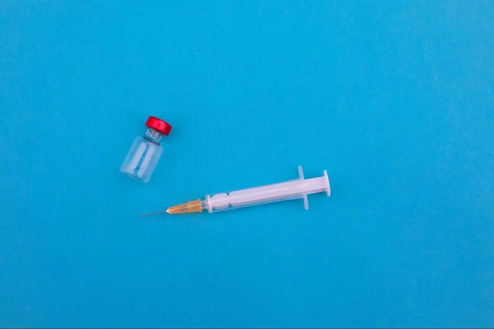 A vial and a syringe against a blue background