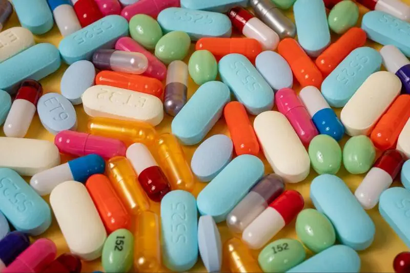 A bunch of colorful pills laid on a yellow surface