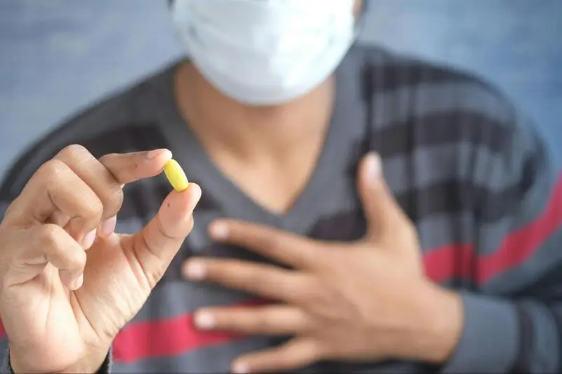 Man holding a yellow pill in his hand