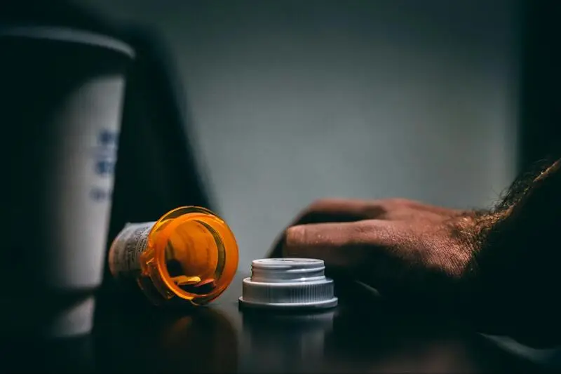 Open orange medication bottle lying on a desk