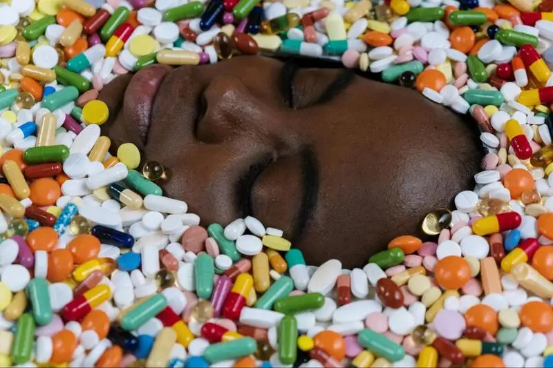 A woman's face emerges from a sea of colorful pills