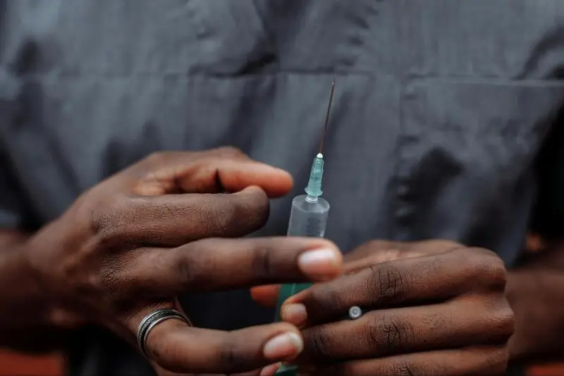 A man holding a syringe in his hand, with the needle visible