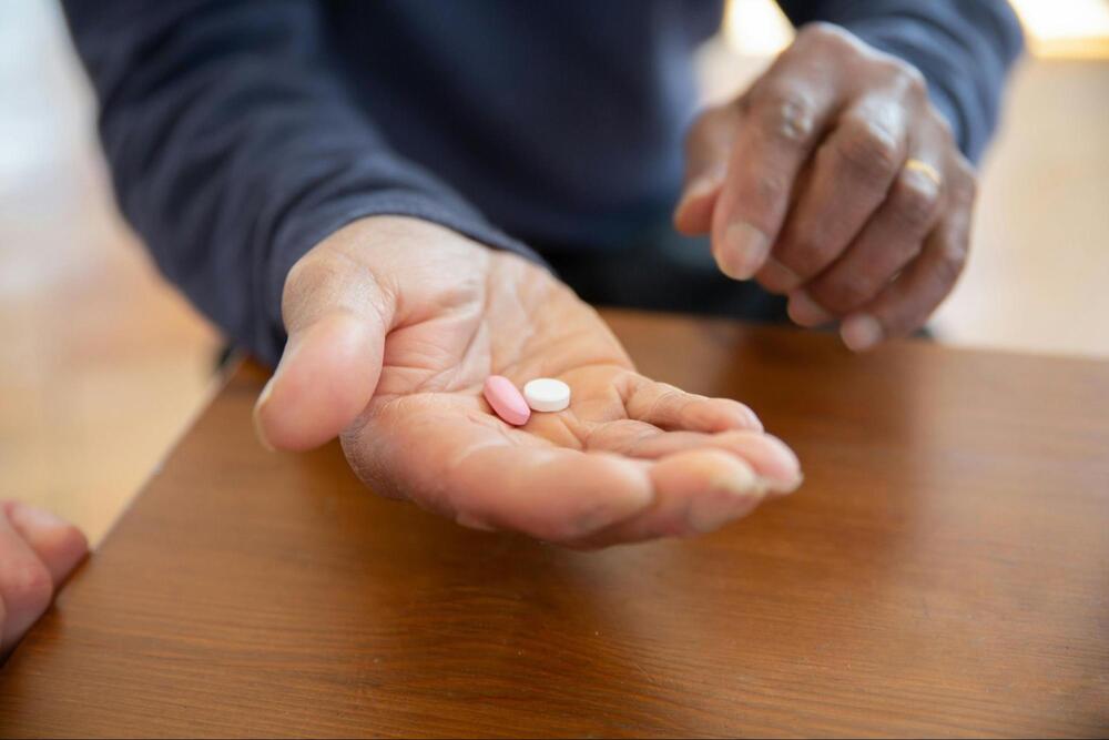 A person holding two pills on their palm